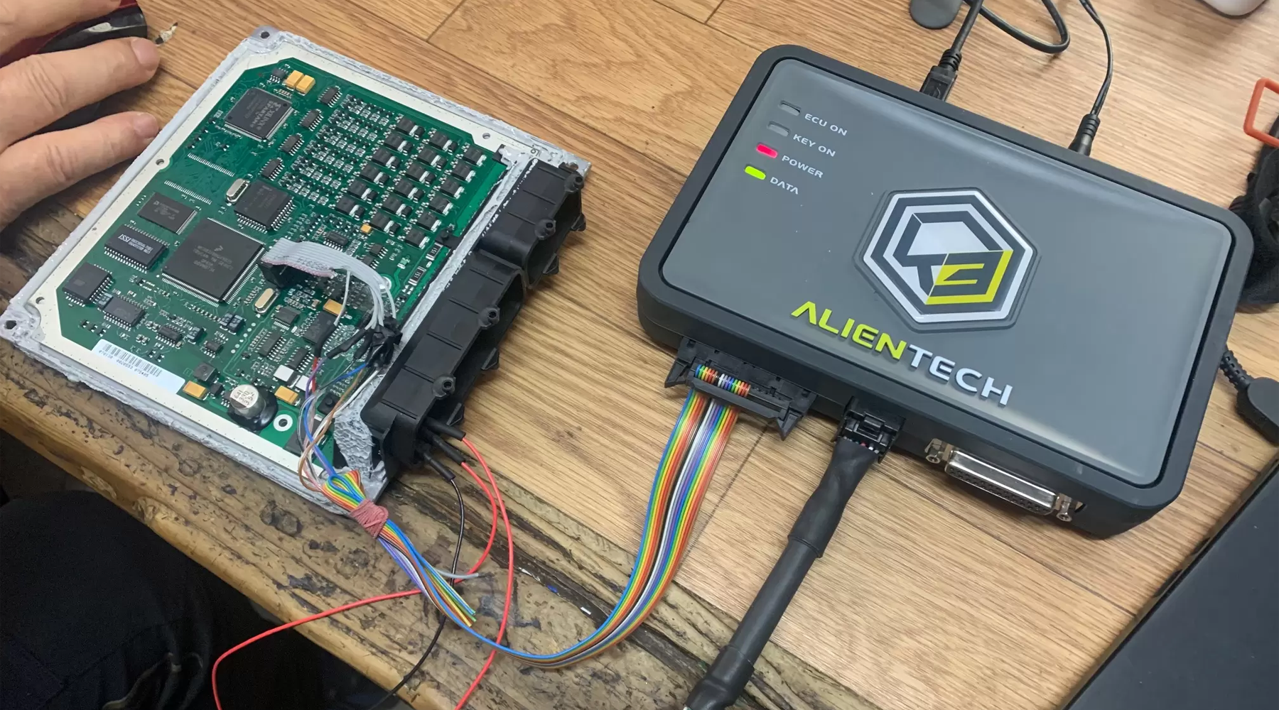 Calculateur moteur ouvert sur un banc, à côté d'un boîtier Autotuner et d'un PC