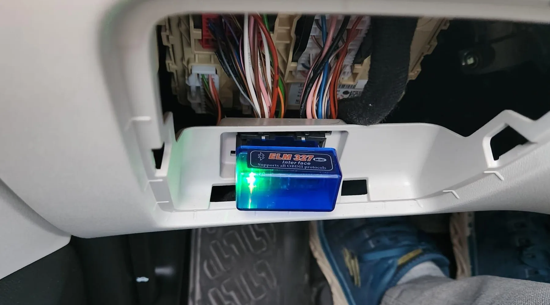 Dongle ELM327 Bluetooth branché sur la prise OBD d'une voiture, smartphone à la main